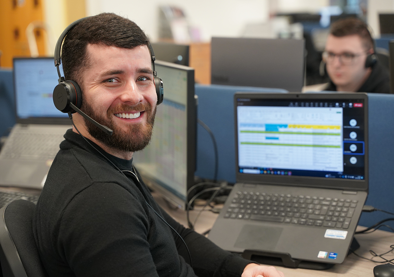 employee sat at desk with laptop and headset