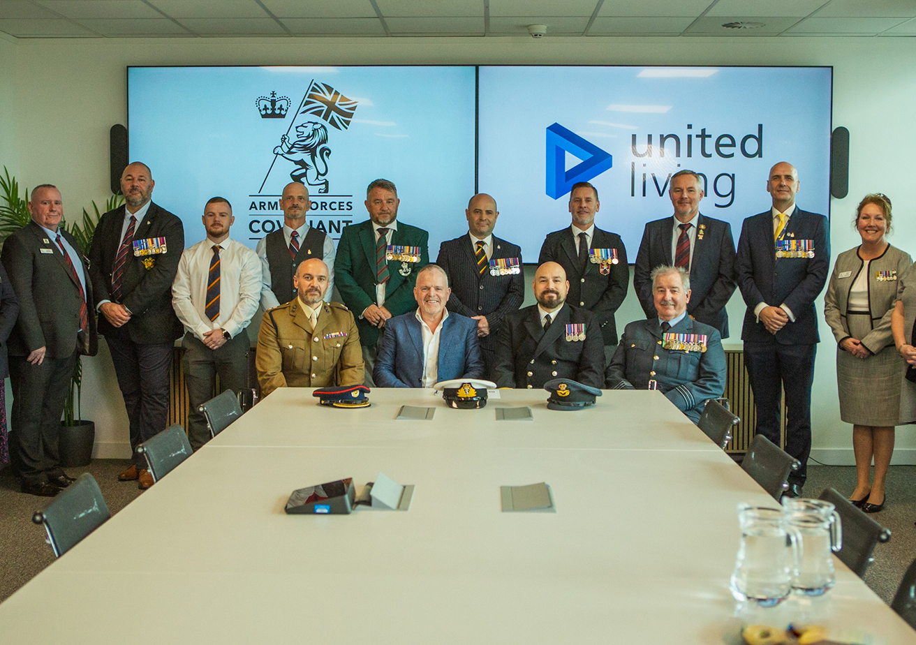 Members of United Living and Armed Forces Covenant gather for group photo in front of company logos